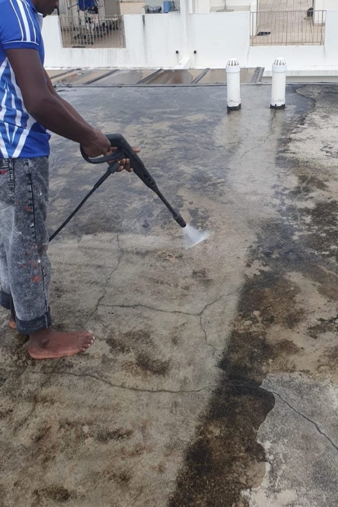 Worker High-Pressure Washing The Ground Level